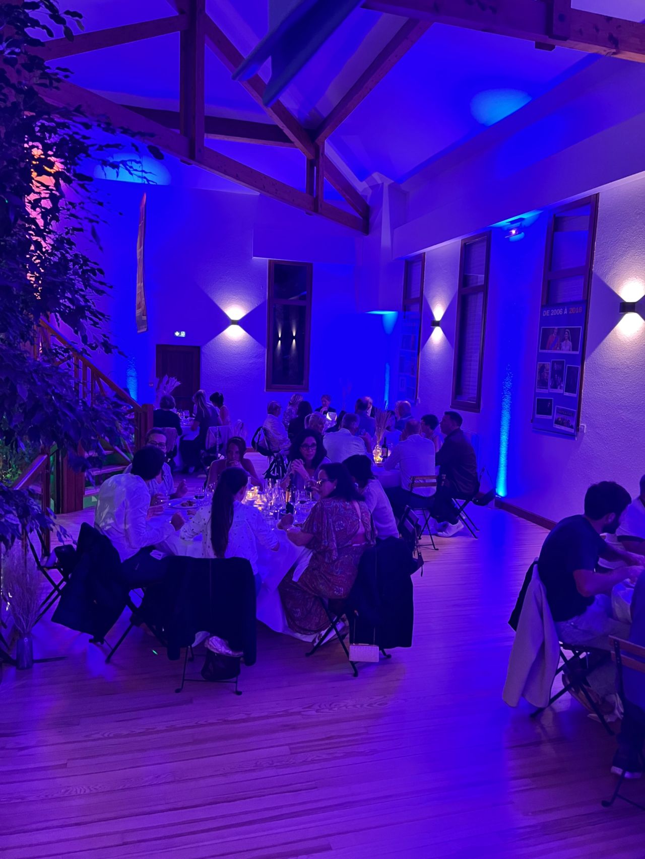 Salle de la soirée GE64 baignée en lumière bleue, la charpente du Pignada habillée de projecteurs pour les 30 ans du groupement.