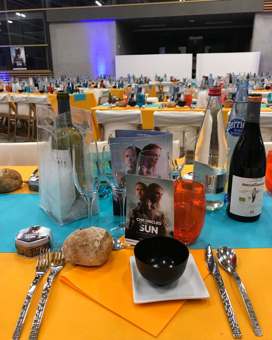 Couvert du dîner de gala de l'espace Arkinova : nappe orange, chemin de table turquoise et carte de la série Chronicles of the Sun.